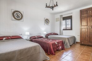 Una habitación con dos camas, un armario de madera, una ventana con rejas y una araña.
