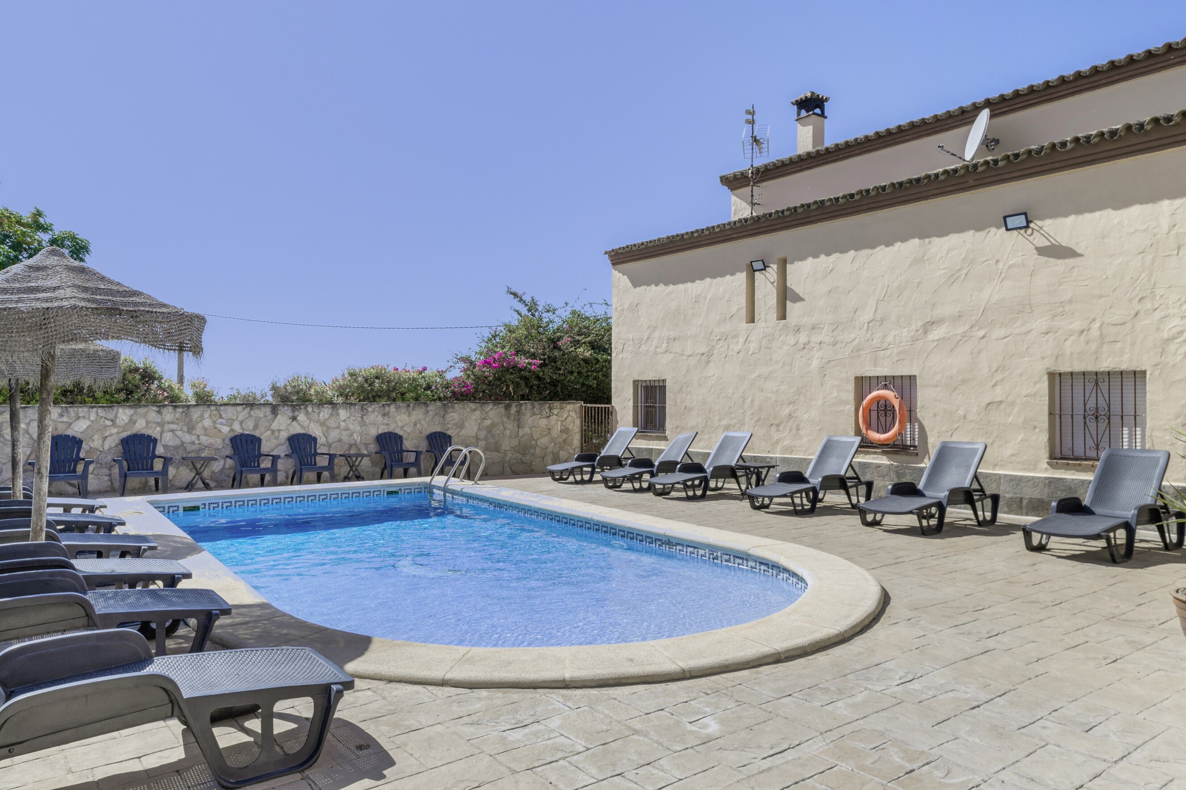 A swimming pool with lounge chairs and a stone wall.