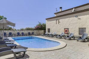 Une piscine avec des chaises longues et un mur en pierre.
