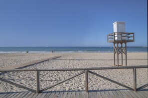 A beach with a lifeguard tower, wooden boardwalk, and ocean view.