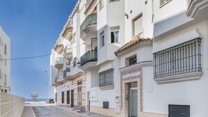 Filas de edificios blancos con balcones, cielo despejado y vista distante al mar.