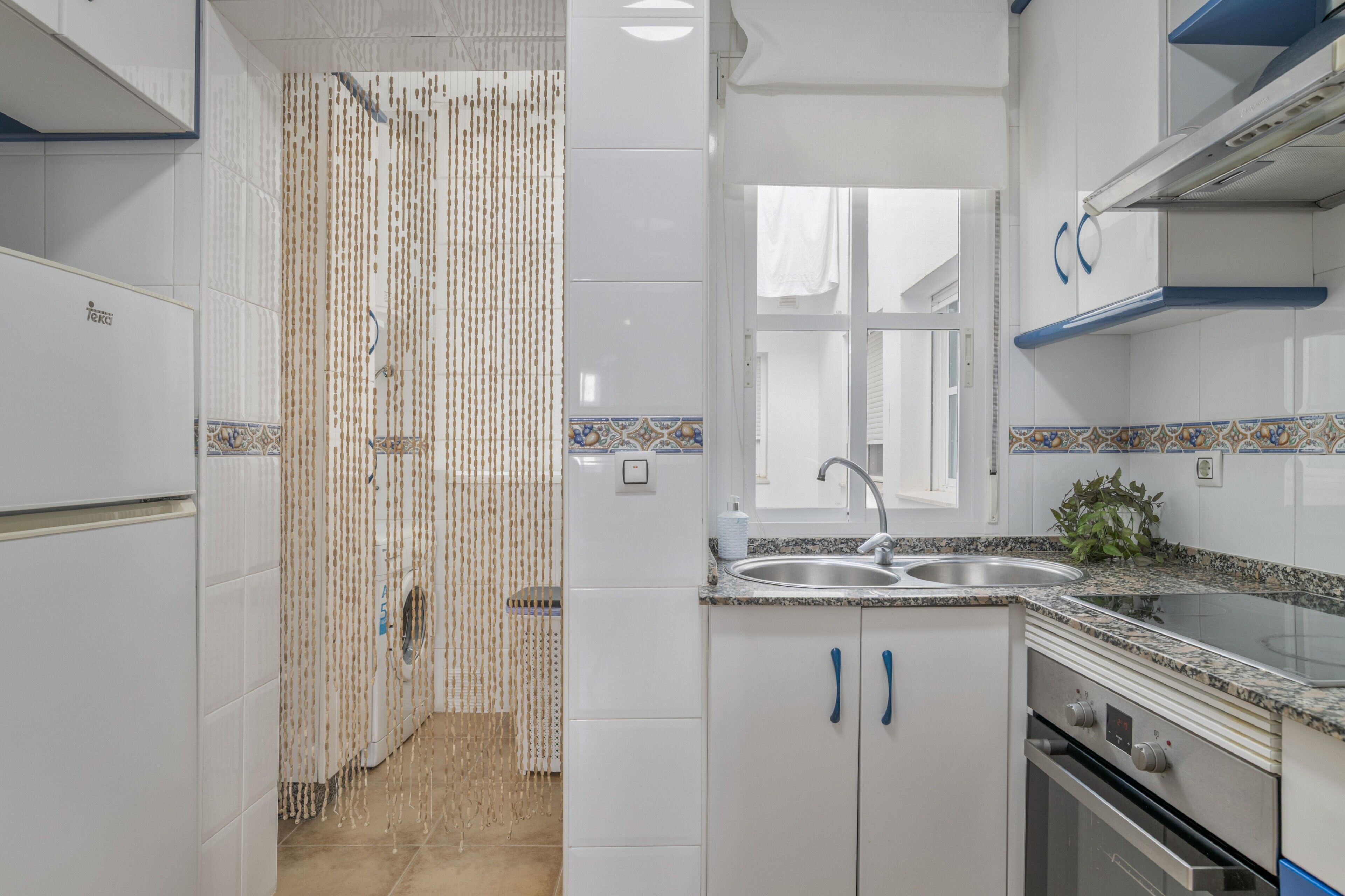 A modern kitchen with white cabinets, a double sink, and a built-in oven.