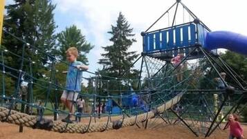 A playground with a rope bridge, climbing net, and a slide.
