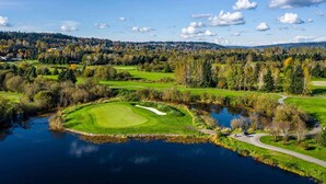 Golfkenttä, jossa on lampi, ja jonka ympärillä on puita ja kukkuloita.