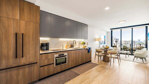 A modern kitchen with wooden cabinets, a built-in oven, and a large window overlooking a cityscape.