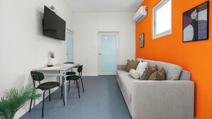 Ein kompakter Wohnbereich mit Essplatz, einer Couch und einem an der Wand befestigten Fernseher.