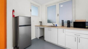 Eine kompakte Küche mit Edelstahlkühlschrank, Mikrowelle und Kaffeemaschine auf der Arbeitsplatte.