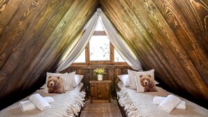 A cozy attic bedroom with two beds, a small table, and a window with curtains. - Osada Góralska Ostoja Pod Gubałówką z Jacuzzi (Poronin)