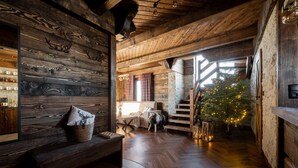 A rustic interior with wooden walls, a stone fireplace, a wooden staircase, and a Christmas tree with lights. - Osada Góralska Ostoja Pod Gubałówką z Jacuzzi (Poronin)