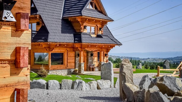 A wooden house with a stone foundation, large windows, and a stone pathway. - Osada Góralska Ostoja Pod Gubałówką z Jacuzzi (Poronin)