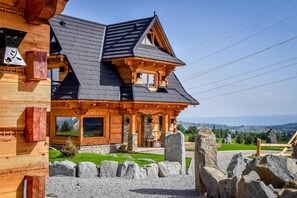 A wooden house with a stone foundation, large windows, and a stone pathway. - Osada Góralska Ostoja Pod Gubałówką z Jacuzzi (Poronin)