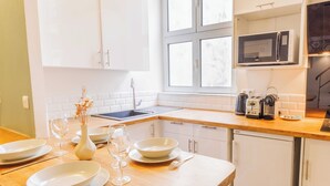 A modern kitchen with white cabinets, a wooden countertop, a microwave, and a dishwasher. - Quiet Apartment 1br/4p - Place des Victoires (Paris)