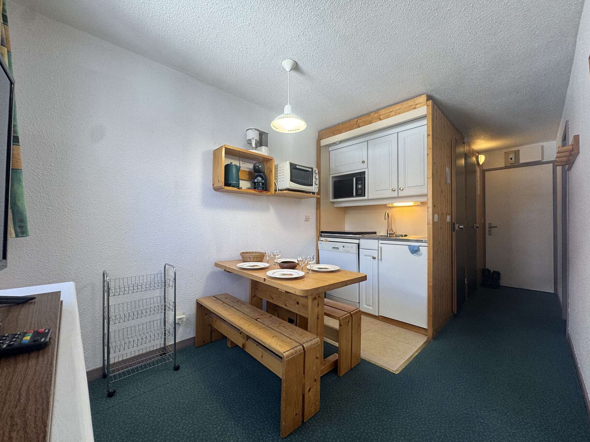 A compact kitchen with wooden furniture, a microwave, and a sink.