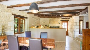 A rustic dining area with a marble table, leather chairs, and exposed wooden beams. - Charming stone cottage with heated pool, pets welcome near Périgueux (Coulounieix-Chamiers)