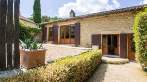 A stone building with a gravel driveway and a well-maintained hedge. - Charming stone cottage with heated pool, pets welcome near Périgueux (Coulounieix-Chamiers)