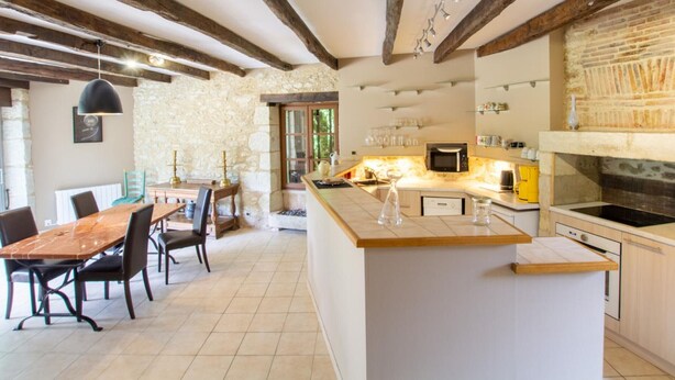 A modern kitchen with a central island, stone walls, and exposed wooden beams. - Charming stone cottage with heated pool, pets welcome near Périgueux (Coulounieix-Chamiers)
