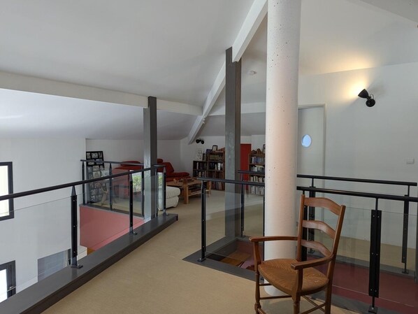A spacious interior with a high ceiling, a central column, and a glass railing overlooking a lower level.