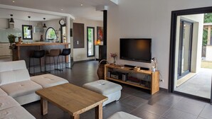 A modern living room with a large TV, a wooden coffee table, and a sofa.