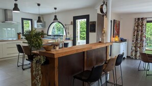 A modern kitchen with a central island, bar stools, pendant lighting, and a view of the outdoors.