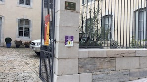 A hotel entrance with a stone wall, a metal gate, and a sign indicating the hotel name and address.