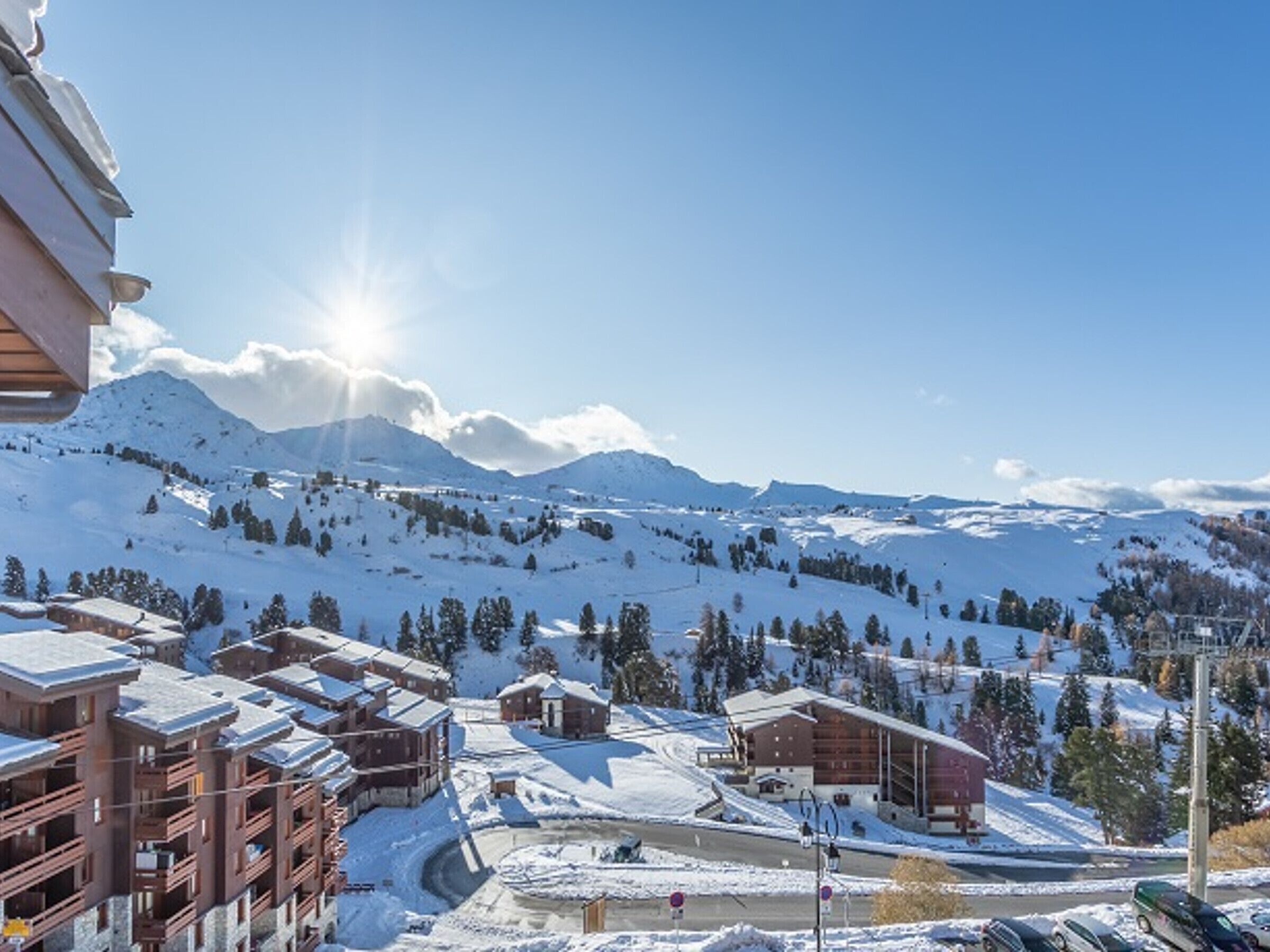 A snow-covered mountain landscape with a ski resort, including buildings and a ski lift.