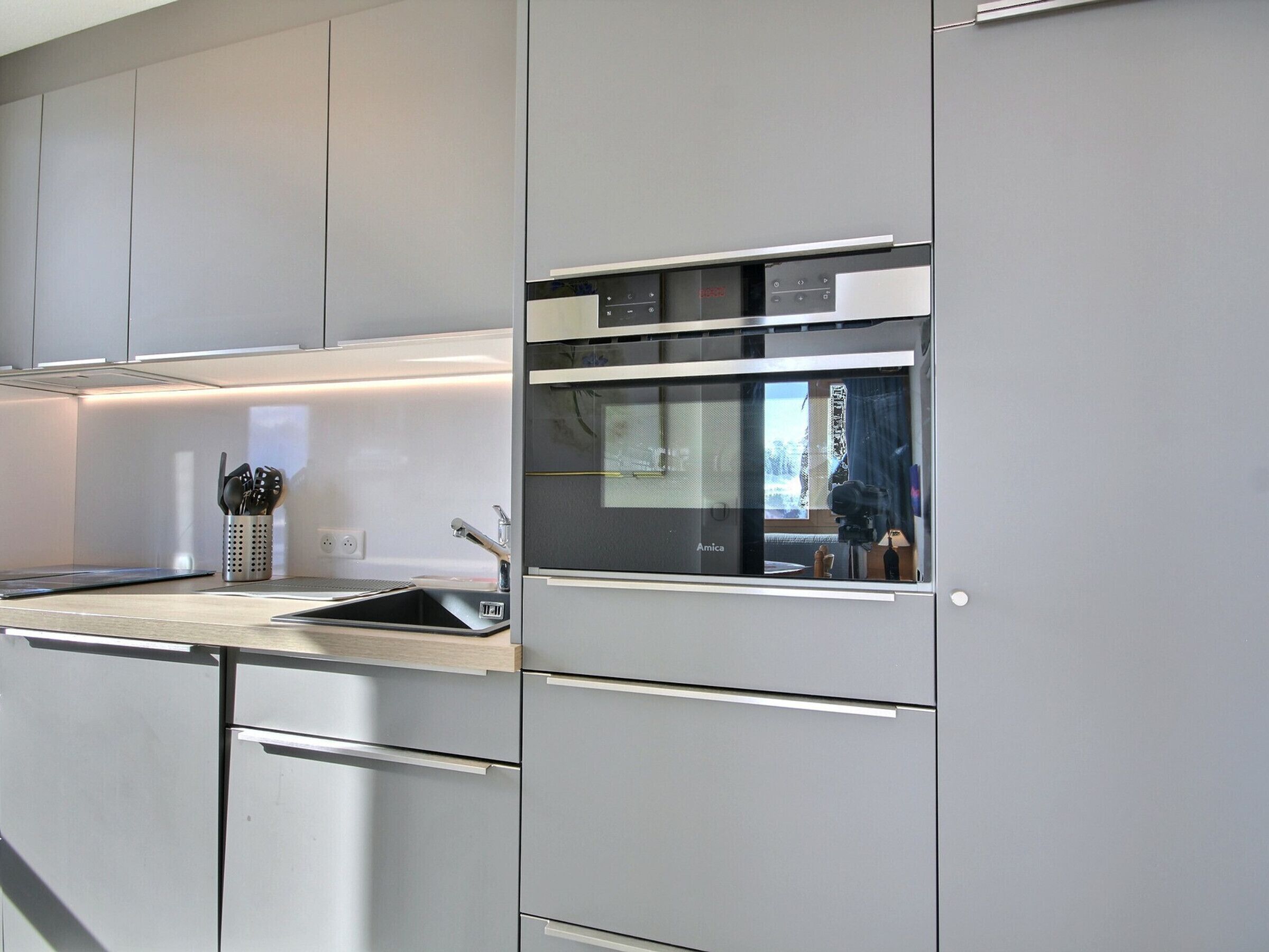 A modern kitchen with stainless steel appliances, a built-in oven, and a sink.