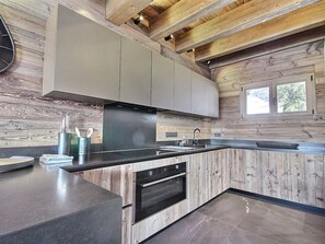 A modern kitchen with wooden walls, a built-in oven, and a window.