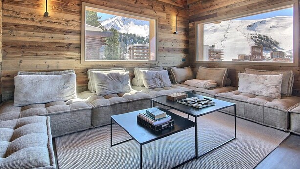 A cozy log cabin interior with a sofa set, a coffee table, and two large windows with mountain views. - New chalet with jacuzzi and sauna (La Plagne)