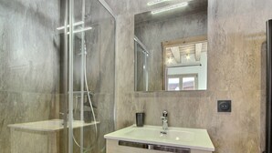 A modern bathroom with a glass-enclosed shower, a vanity with a sink, and a mirror above the sink. - New chalet with jacuzzi and sauna (La Plagne)
