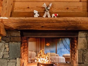 A cozy cabin interior with a stone fireplace, wooden beams, and a bed with striped bedding.