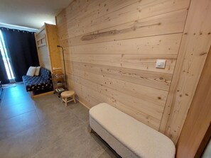 A room with a wooden wall, a sofa, a small stool, and a bench.