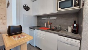Una cocina moderna con armarios blancos, un microondas, un lavavajillas Bosch y un tostador sobre una mesa de madera.