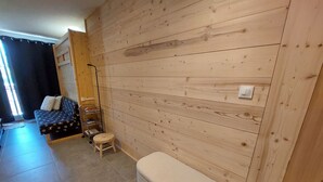 Una habitación con pared de madera, un sofá, un taburete pequeño y un banco.