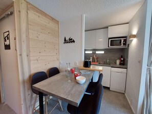 A compact kitchen with a wooden table and chairs, a microwave, and a dishwasher.