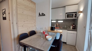Una cocina compacta con una mesa y sillas de madera, un microondas y un lavavajillas.