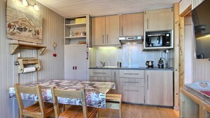 A compact kitchen with wooden cabinets, a microwave, and a small dining area with a table and chairs.