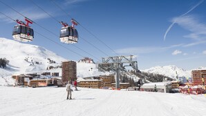 A ski resort with cable cars, buildings, and a snowy landscape.