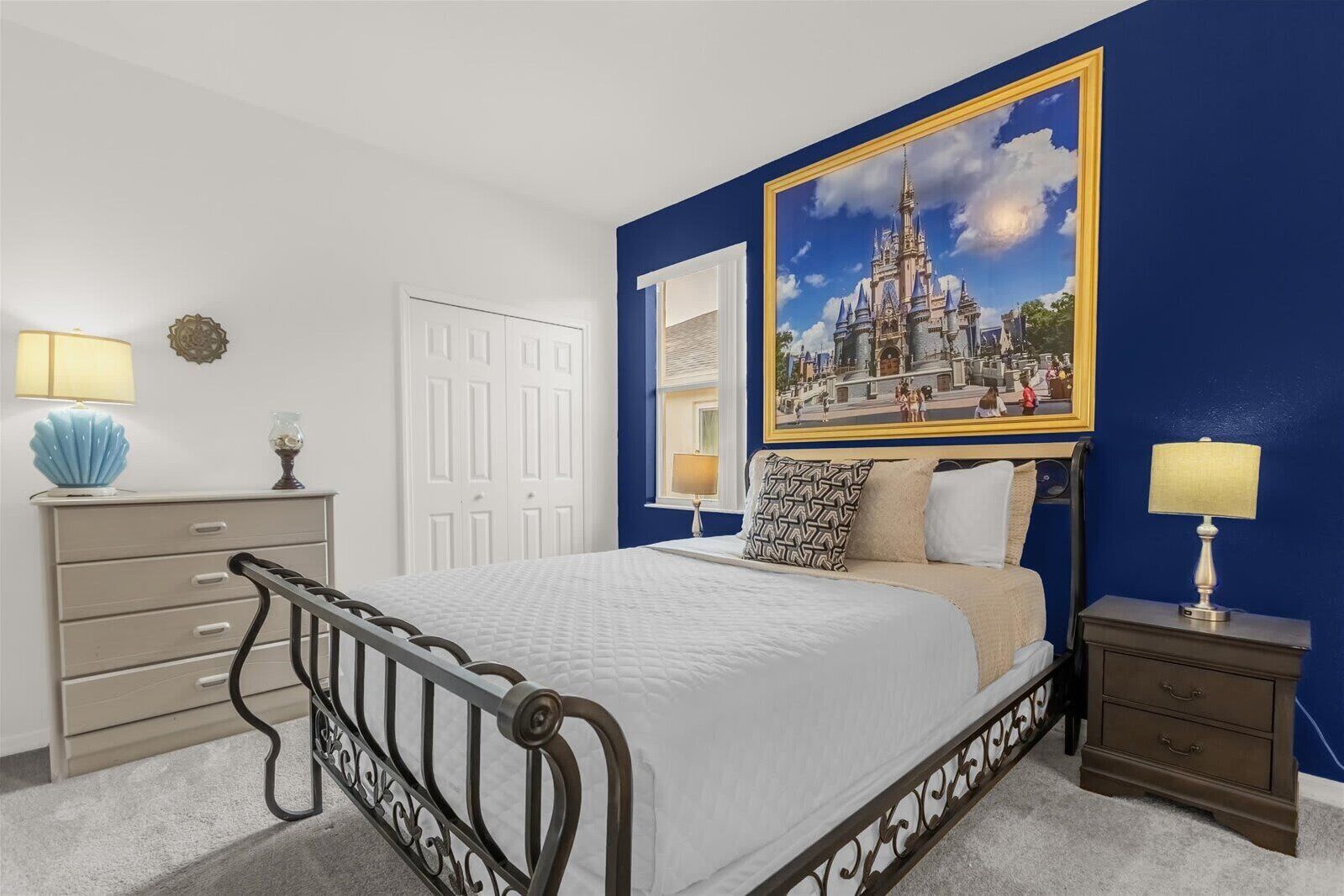 A bedroom with a bed, bedside tables, a dresser, and a large framed picture on the wall.