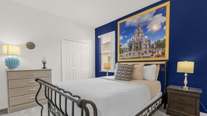 Une chambre à coucher comprenant un lit, des tables de chevet, une commode et un grand tableau encadré accroché au mur.