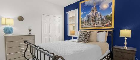 A bedroom with a bed, bedside tables, a dresser, and a large framed picture on the wall.
