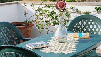 A table with a book, a decorative glass vase with a flower, and a potted plant.