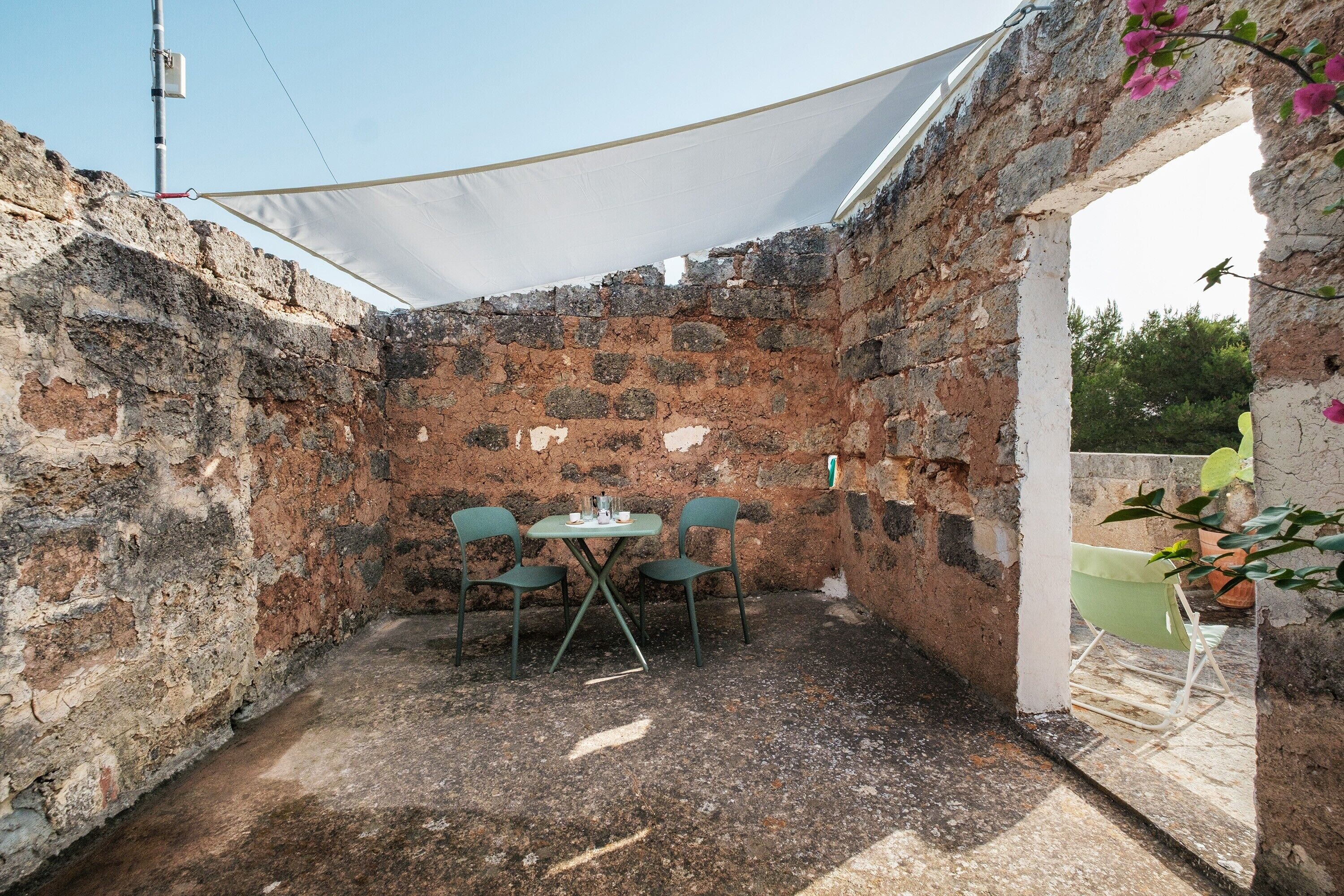 Un espacio de descanso al aire libre de estilo rústico con una mesa y sillas, rodeado de muros de piedra.