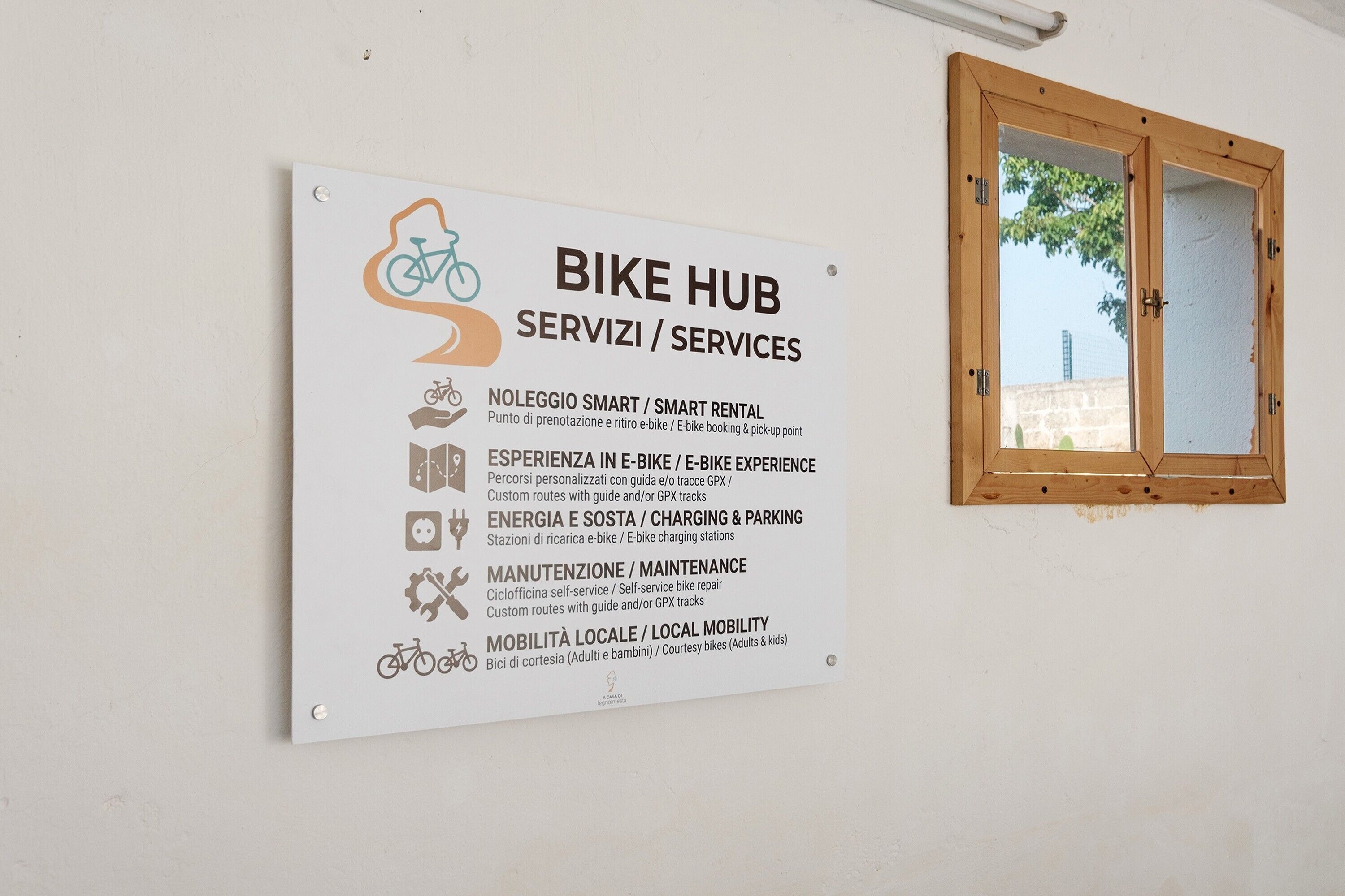 Un panneau indiquant un centre de services pour vélos, offrant des prestations telles que la location de vélos connectés, des essais de vélos électriques, des bornes de recharge, des services d’entretien et des solutions de mobilité locale.