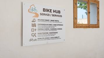 Un panneau indiquant un centre de services pour vélos, offrant des prestations telles que la location de vélos connectés, des essais de vélos électriques, des bornes de recharge, des services d’entretien et des solutions de mobilité locale.