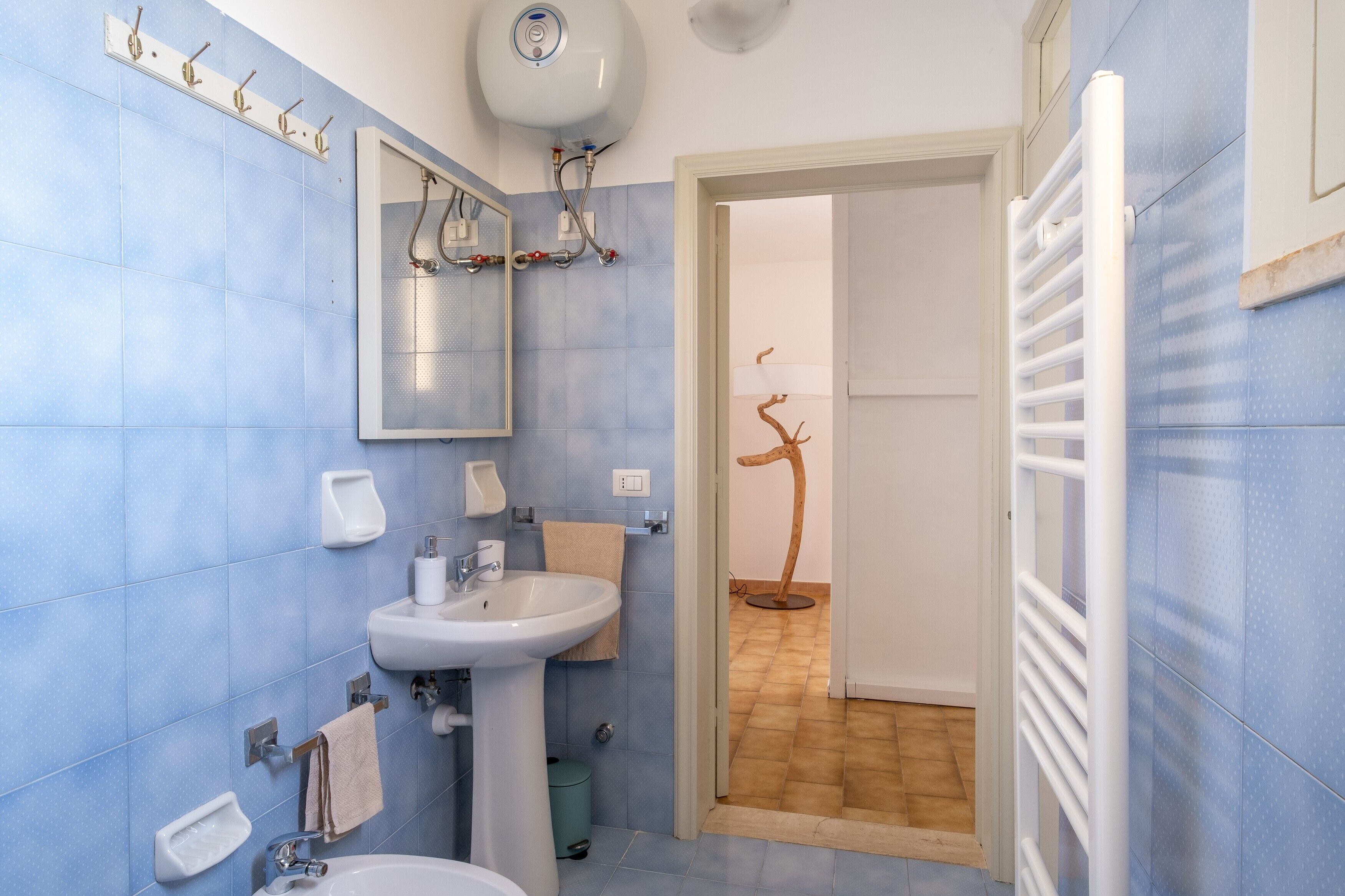 Een badkamer met een wastafel, spiegel, handdoekhouder en douche.