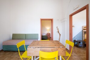 Una habitación con una mesa de madera y sillas amarillas, un sofá verde y un armario de madera.