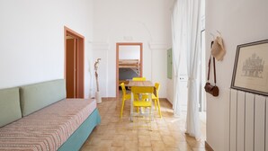 Een kamer met een bank, een eettafel met gele stoelen, een houten deur en een lijst met een foto aan de muur.