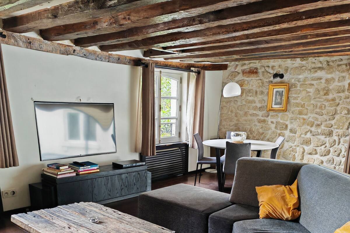 A living room with a sofa, a coffee table, a TV, and a stone wall.