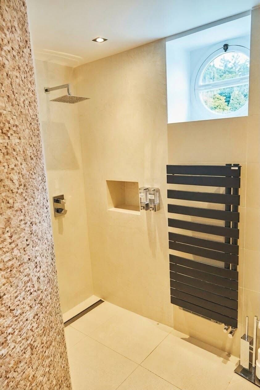 Een moderne badkamer met een douche, een inbouw raam en een handdoekhouder.