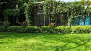 Zona verde bien cuidada con un sendero despejado, rodeada de arbustos y árboles densos.